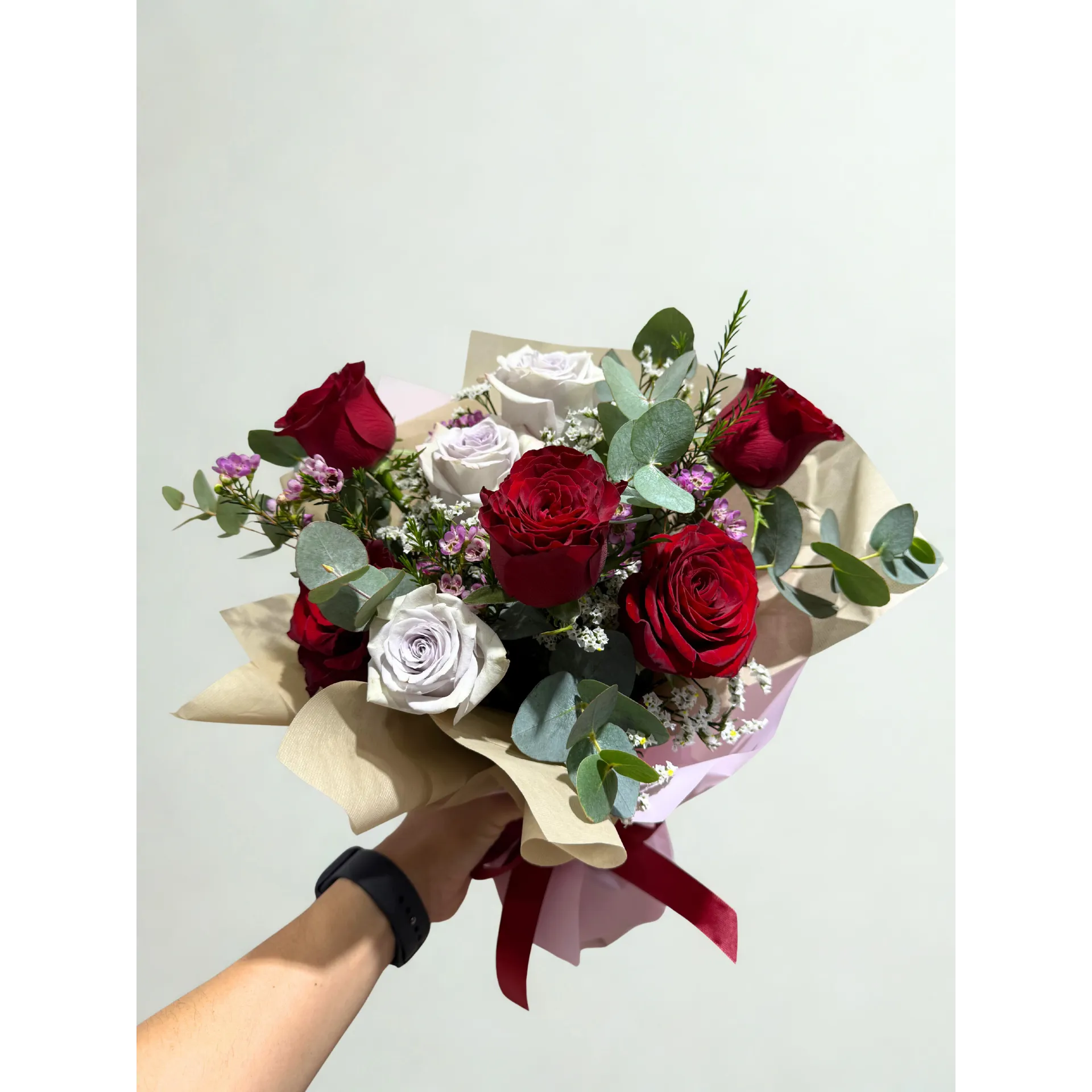 Beautiful hand-tied floral bouquet with red roses, peach carnations, white filler, and eucalyptus
